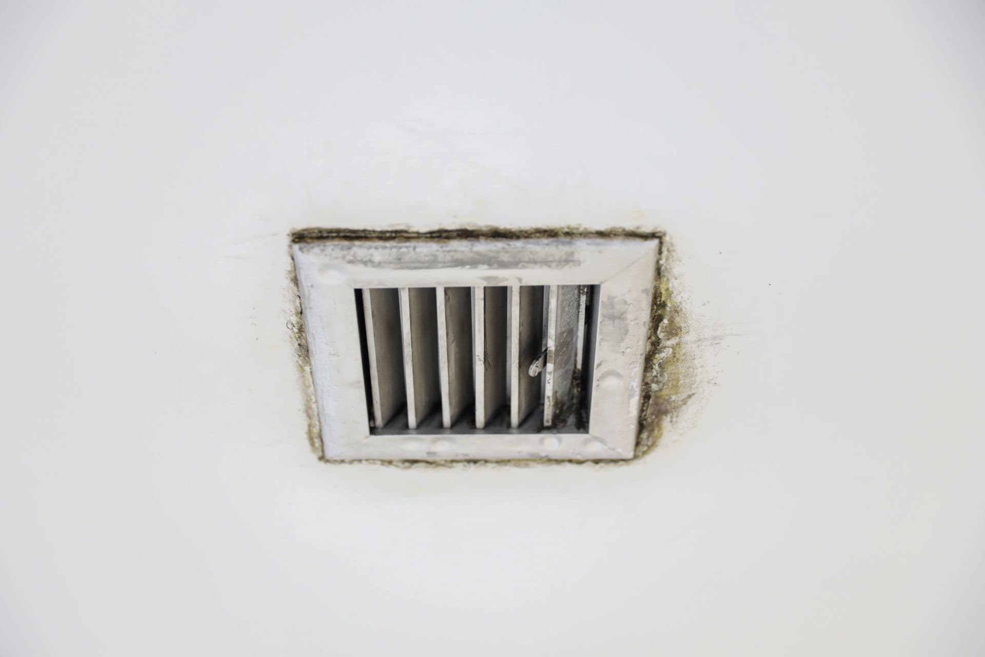 A brown water stain spreading across a ceiling below a leaking air-conditioning unit