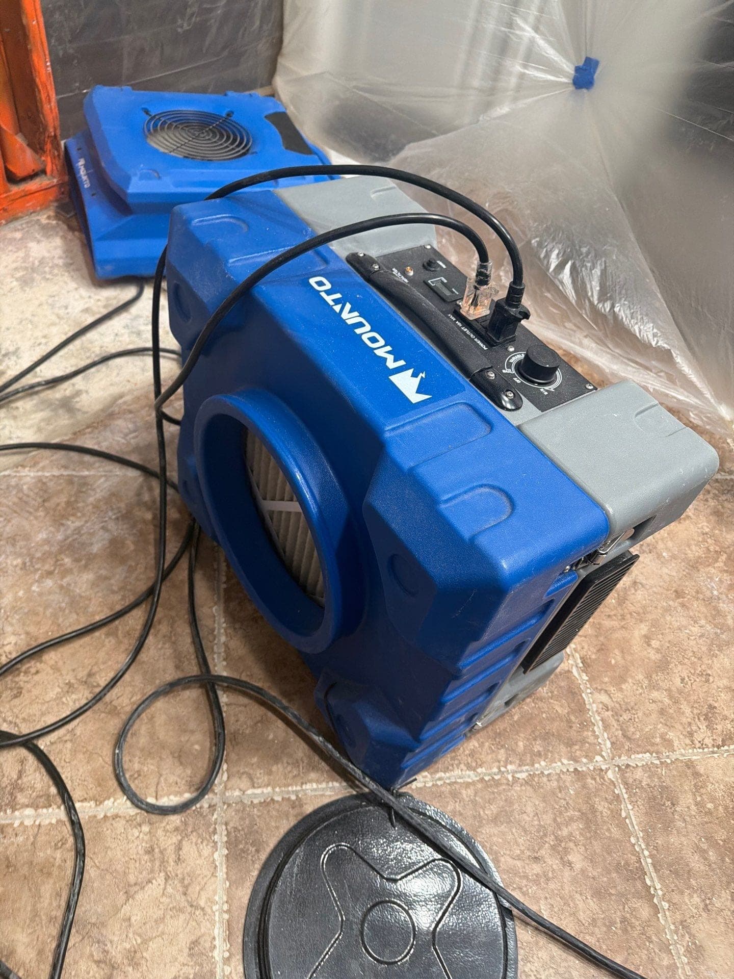 Air movers and a dehumidifier drying a tile floor after water damage