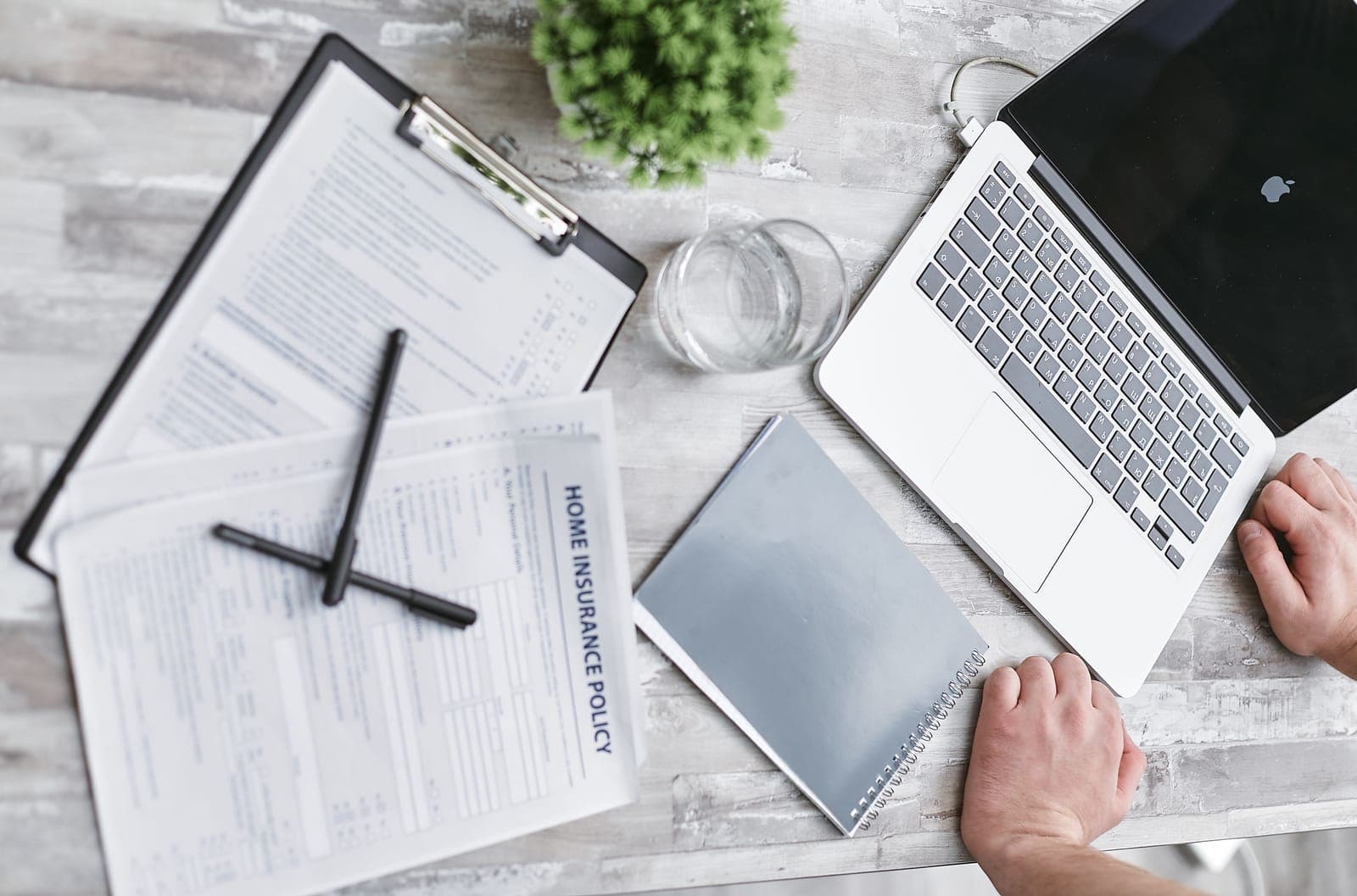 A home insurance policy and paperwork on a desk while a claim is documented