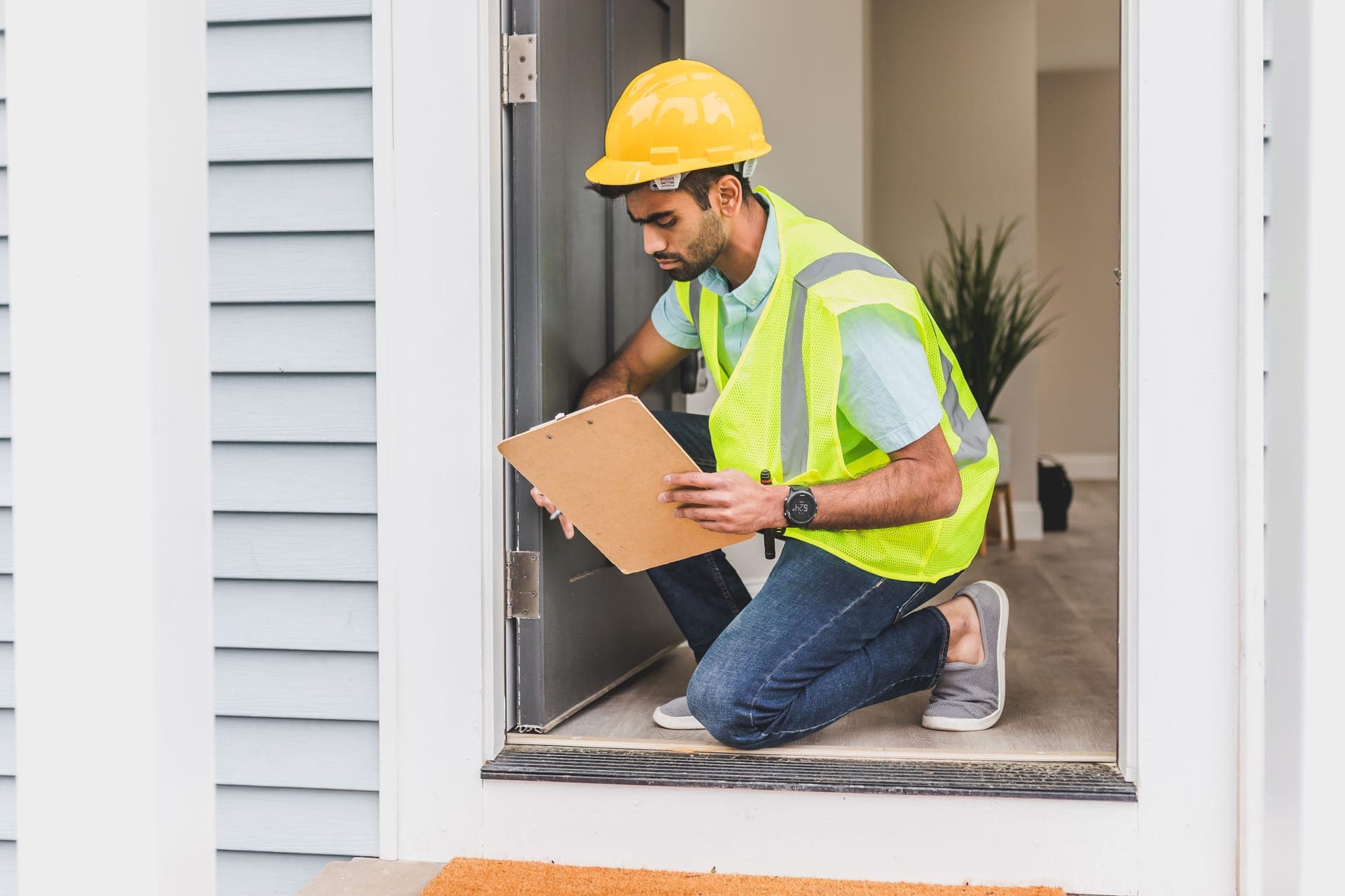 A field rep documenting a home on a clipboard during a damage-claim assessment