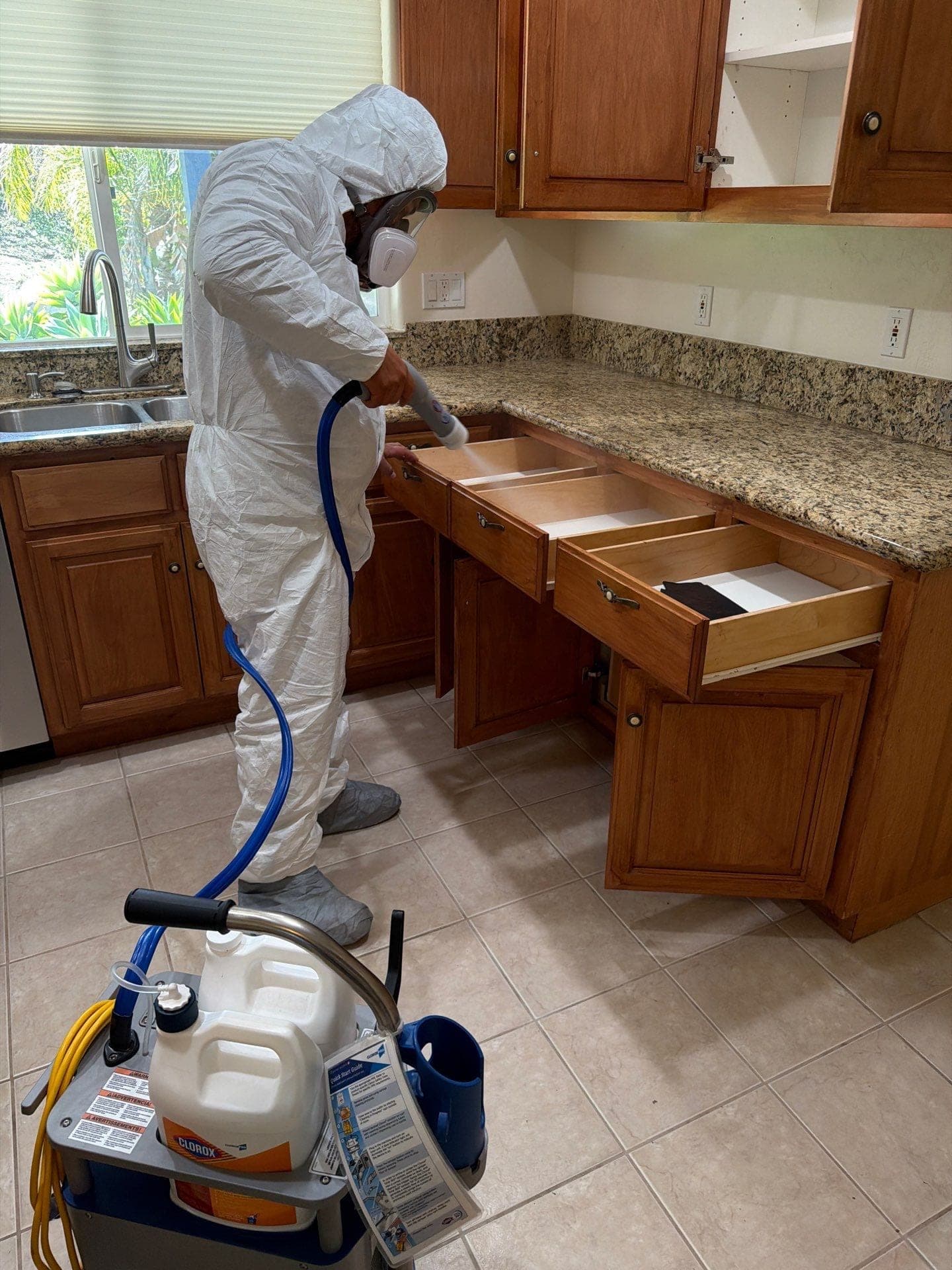 A technician in protective gear treating cabinets during mold remediation