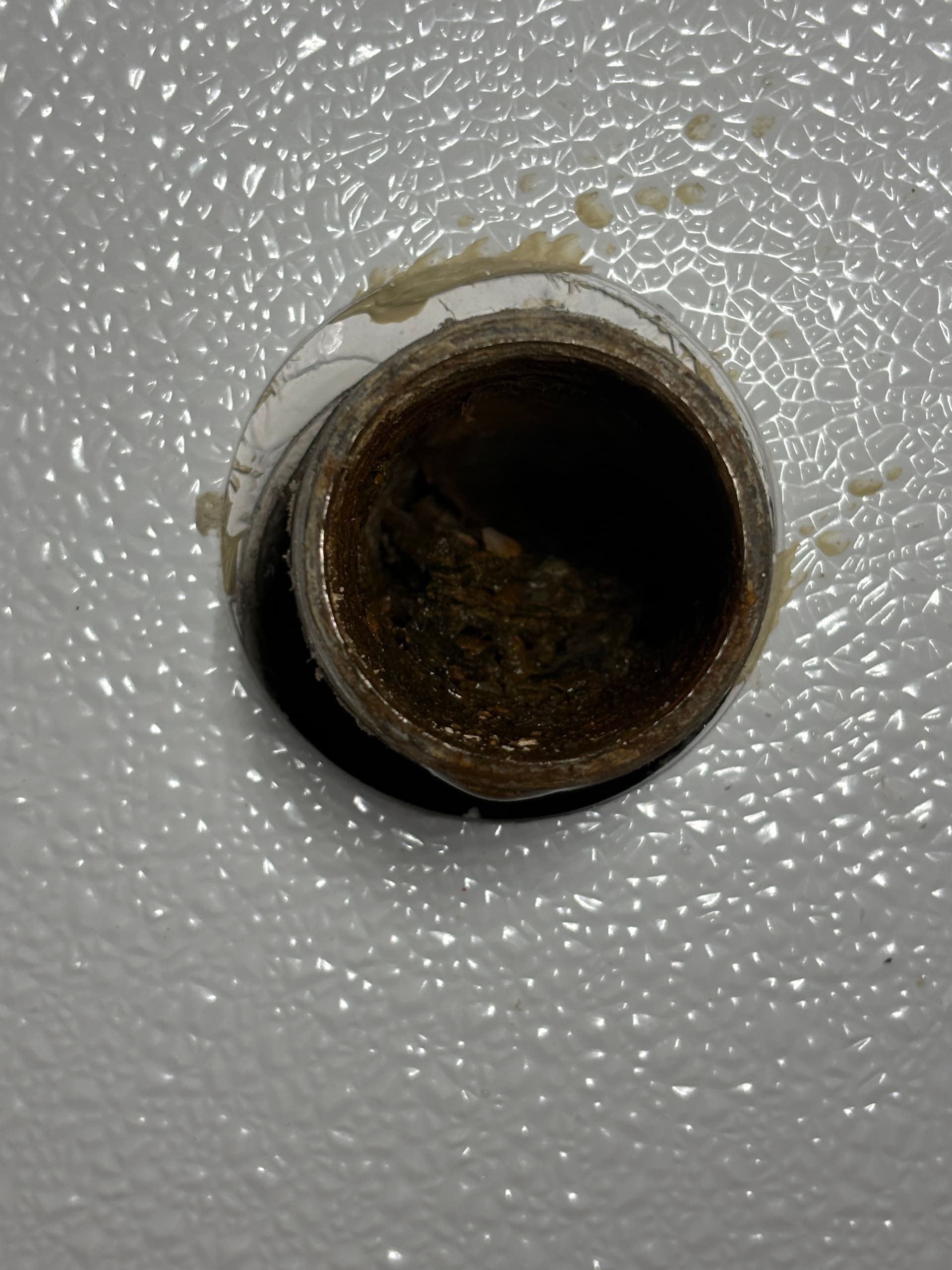 An open floor drain pipe with buildup at the opening