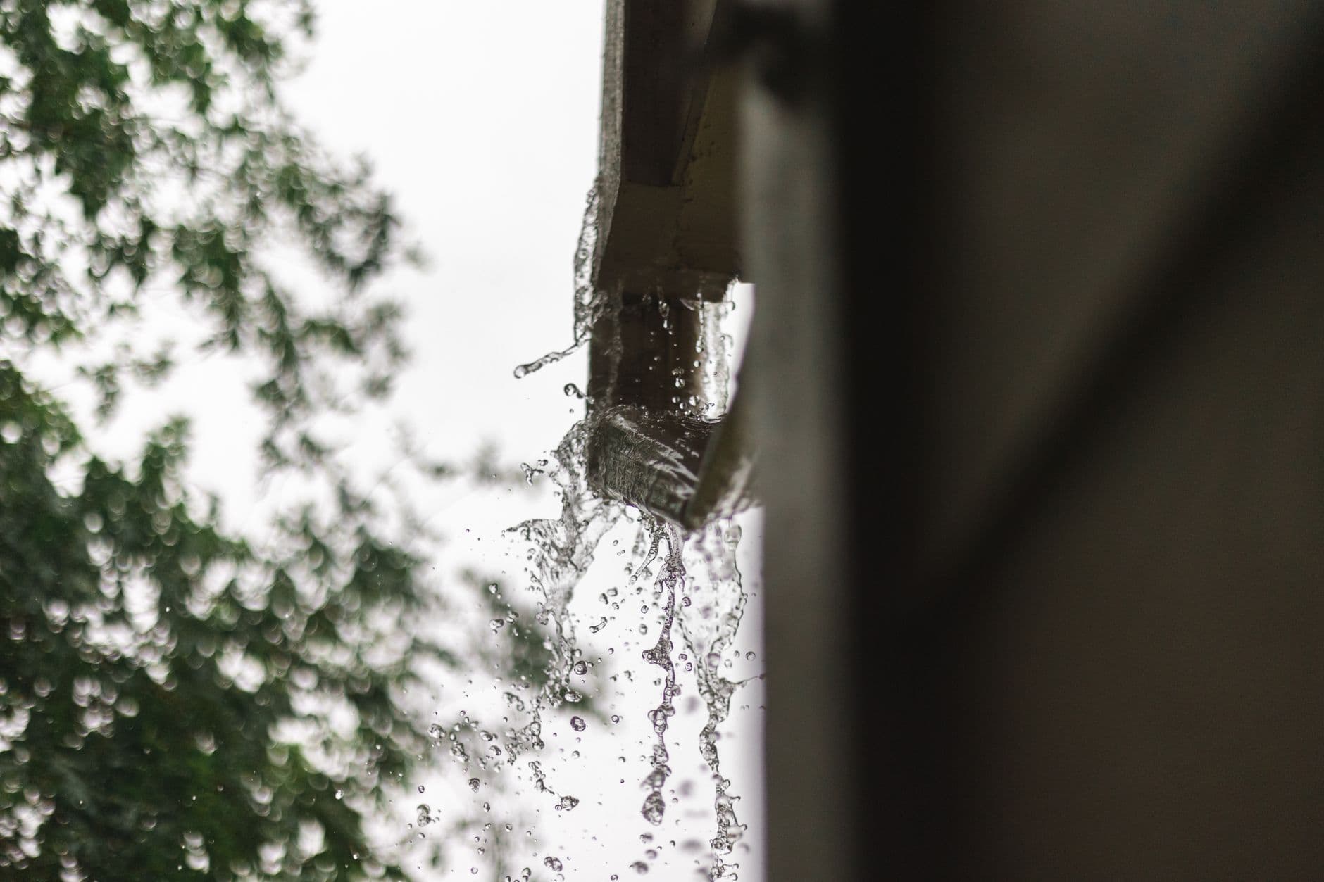 Rainwater pouring off a roof edge during a heavy storm
