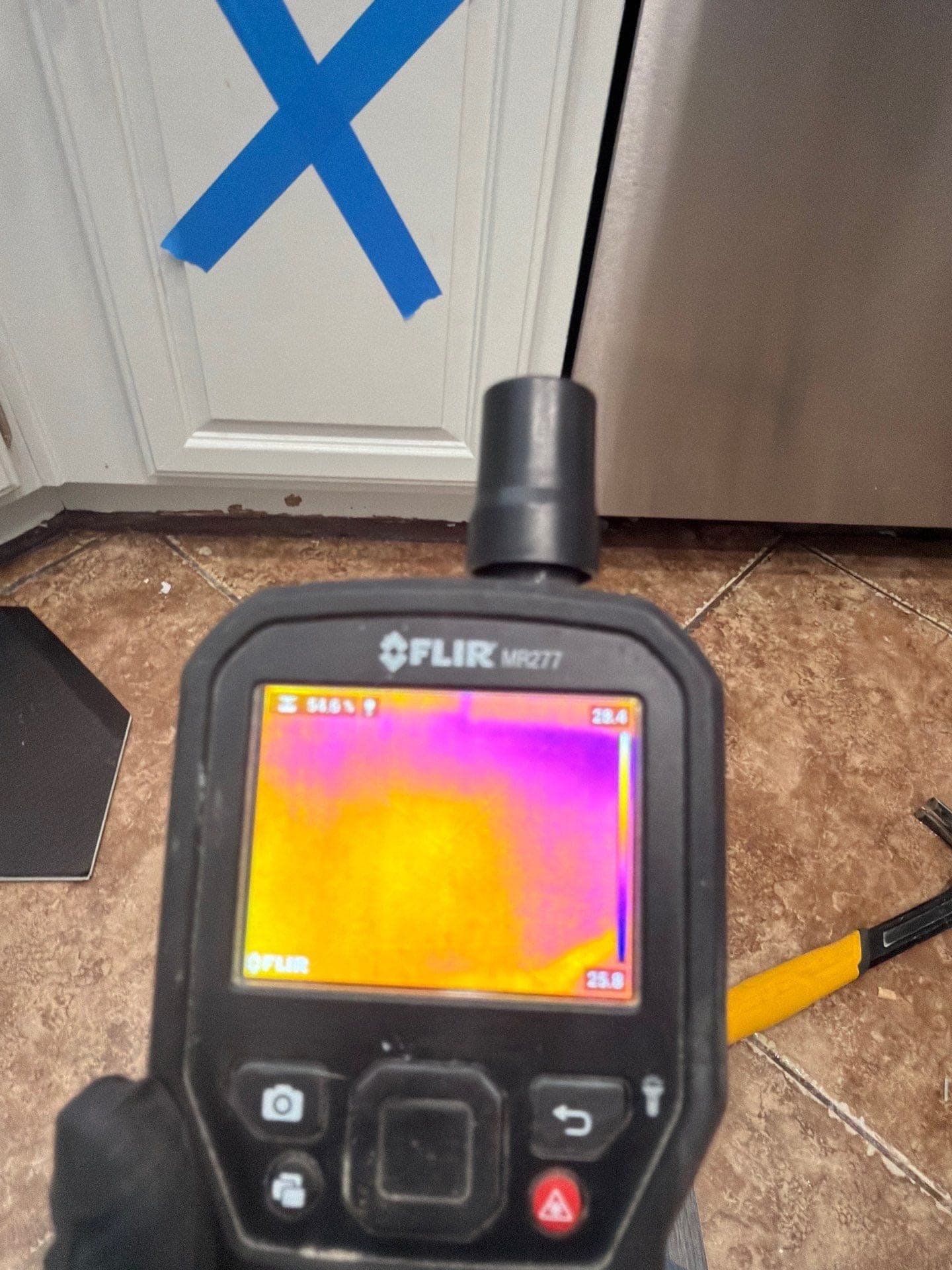 A technician reading a wall with a thermal camera to find hidden moisture