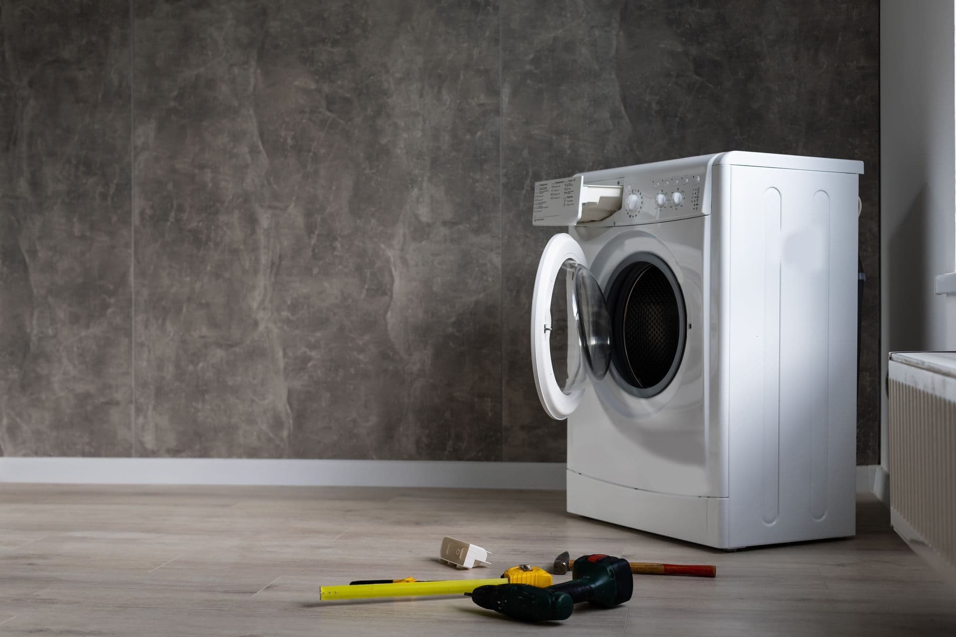 Water leaking from a broken washing machine and pooling across a laundry-room floor