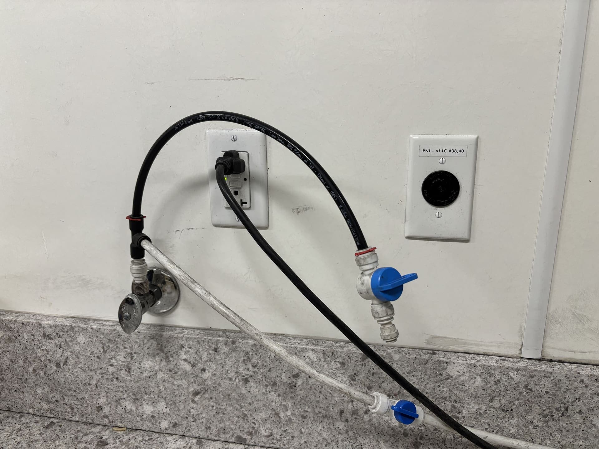 A washing-machine water-supply hose and valve connection at the wall