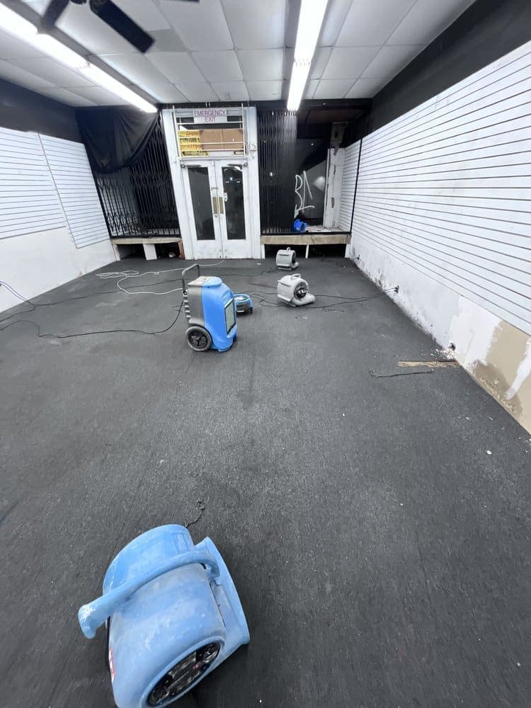 Air movers and a dehumidifier drying a commercial storefront during a Resolve Residential Restoration emergency response