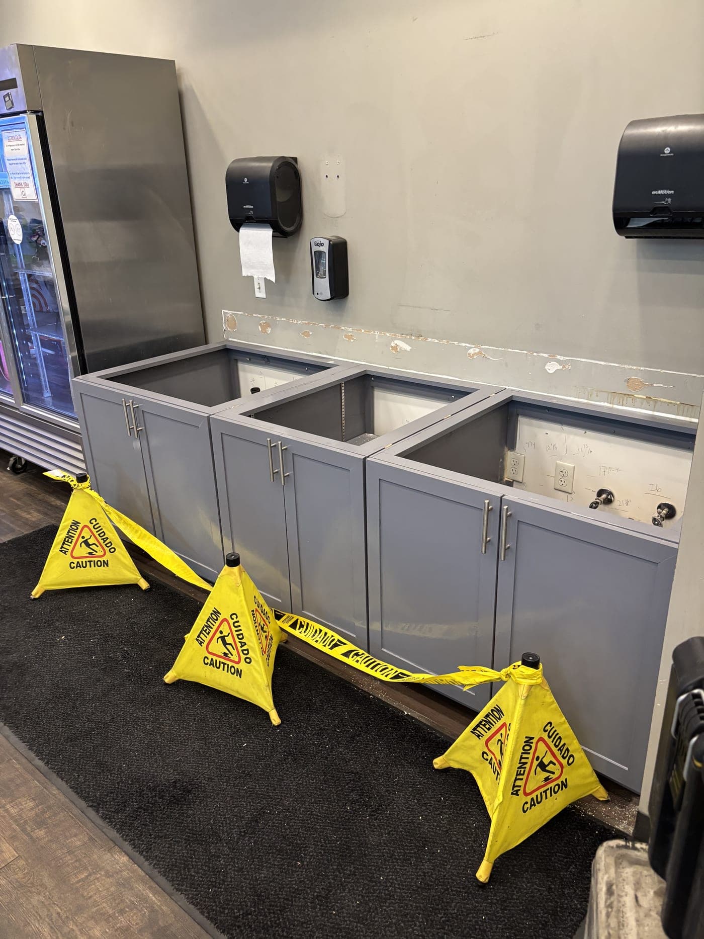 Torn-out cabinetry and wet-floor signage during a Resolve Residential Restoration commercial water mitigation