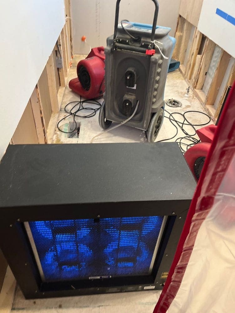 Containment sheeting and an air scrubber set up in a gutted bathroom during a Resolve Residential Restoration mold job