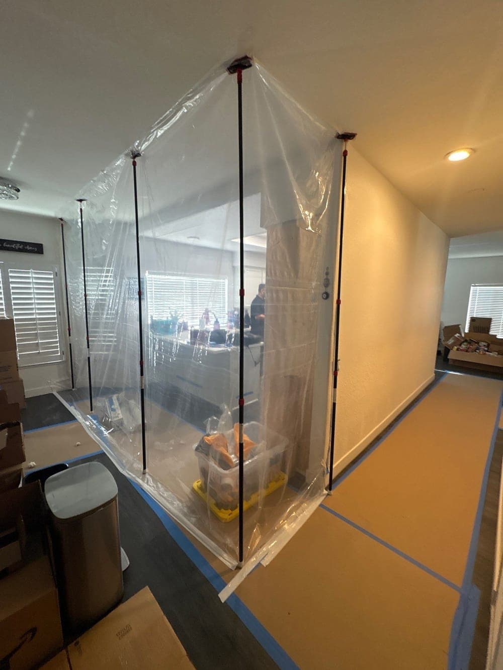 Plastic sheeting held on zip poles sealing a kitchen doorway before demolition on a Resolve Residential Restoration water job