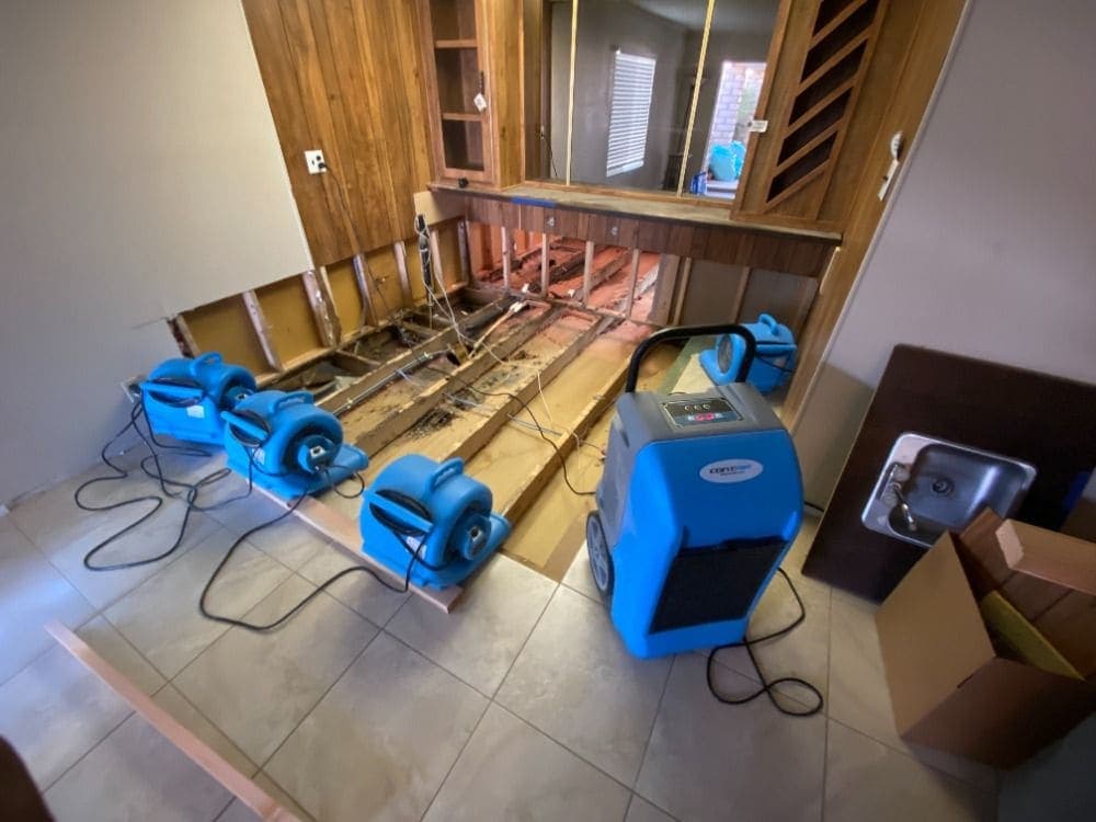 A floor opened to the joists with air movers and a dehumidifier running during a Resolve Residential Restoration structural dry-out
