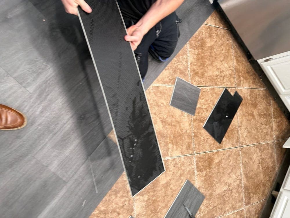 A Resolve Residential Restoration technician lifting wet planks away from the subfloor