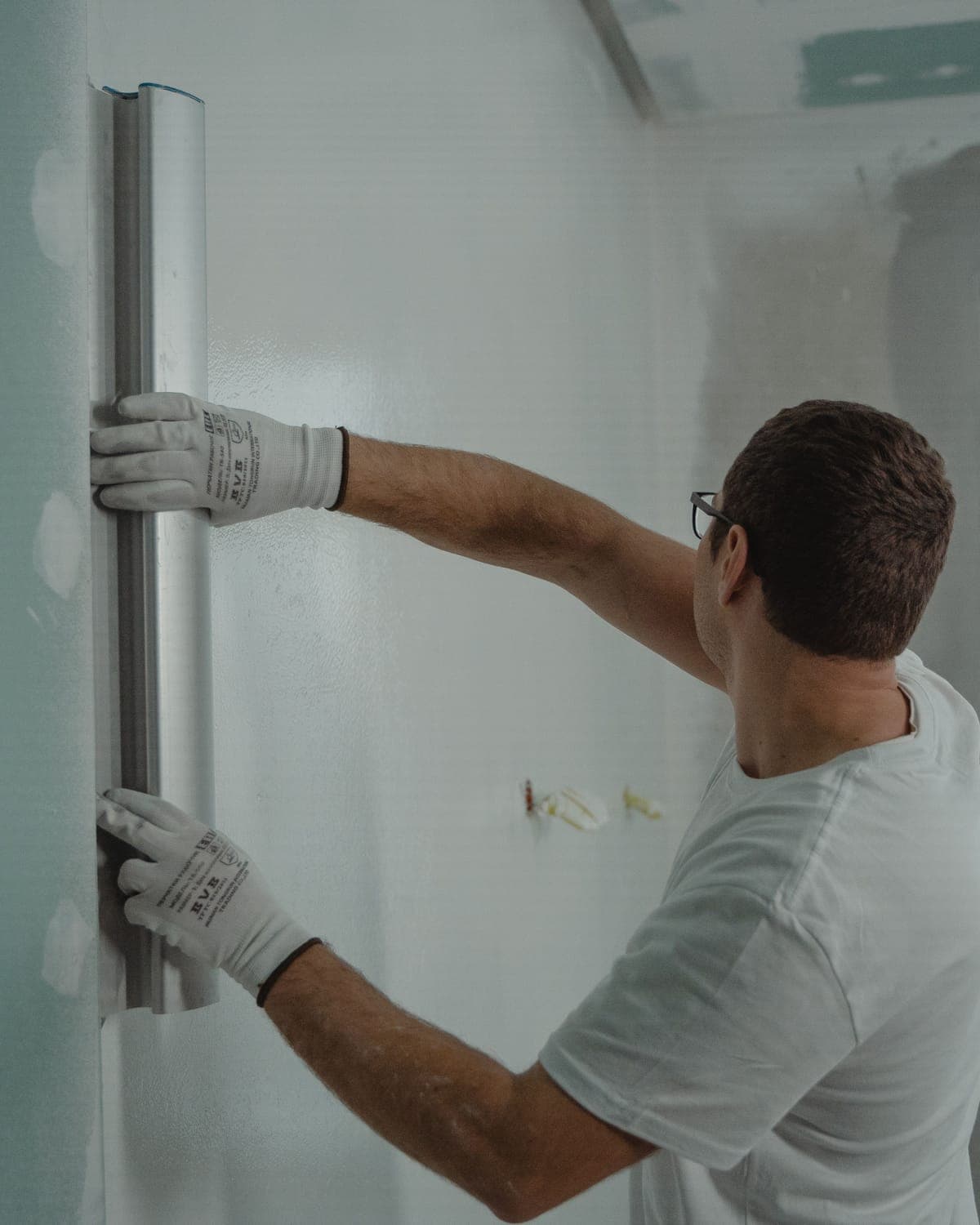 A restoration technician in gloves working on a wall during a repair