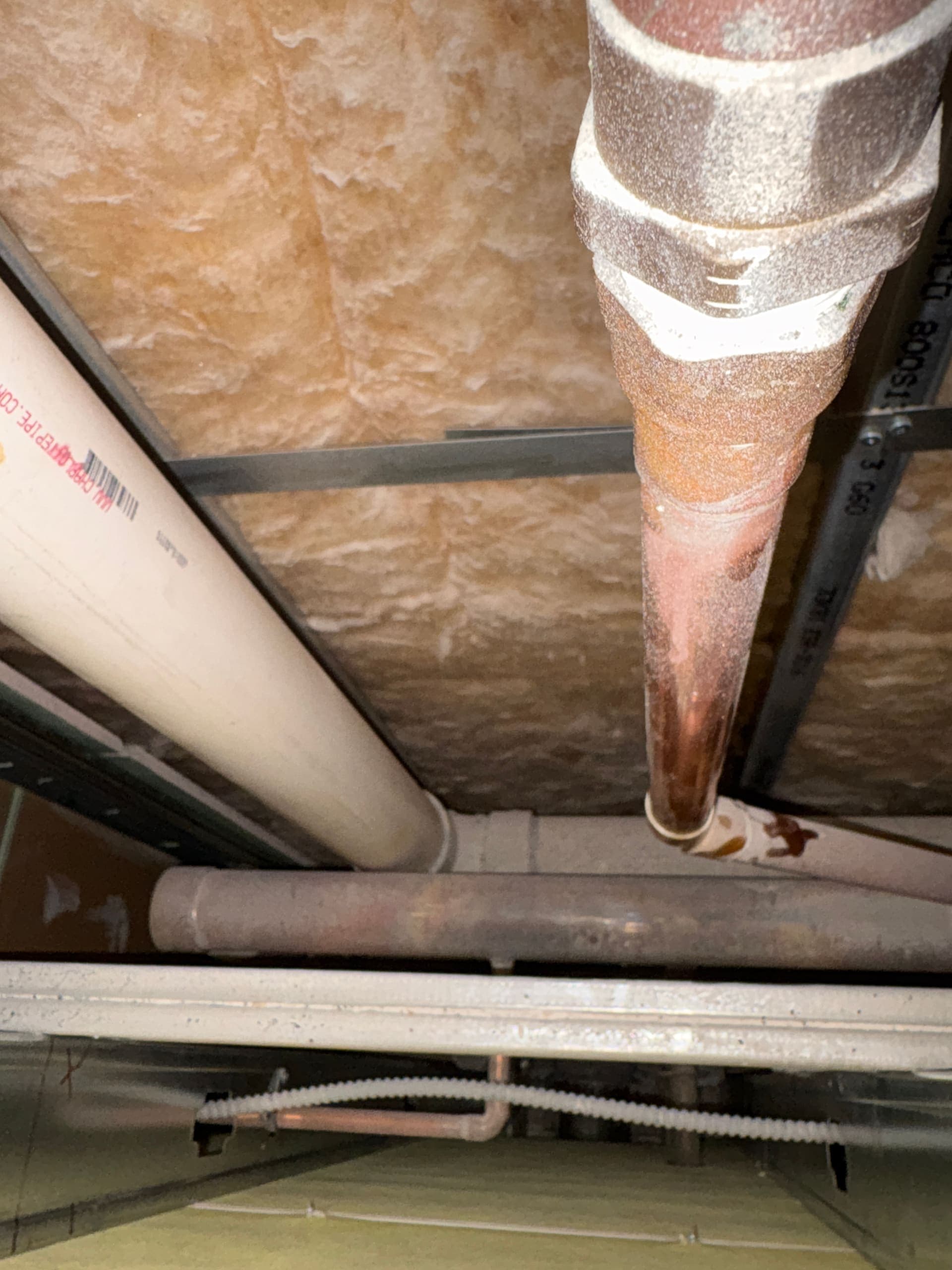 PVC and copper pipes running through a ceiling cavity
