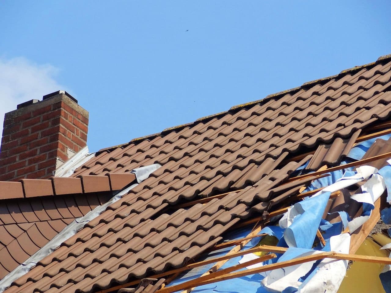 A tile roof torn up by wind-driven storm debris on a Southern California home