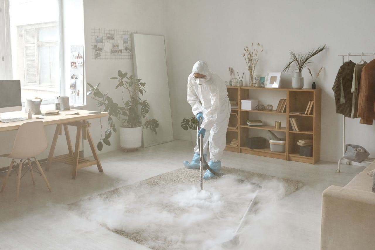 A worker in a protective suit treating a room for mold