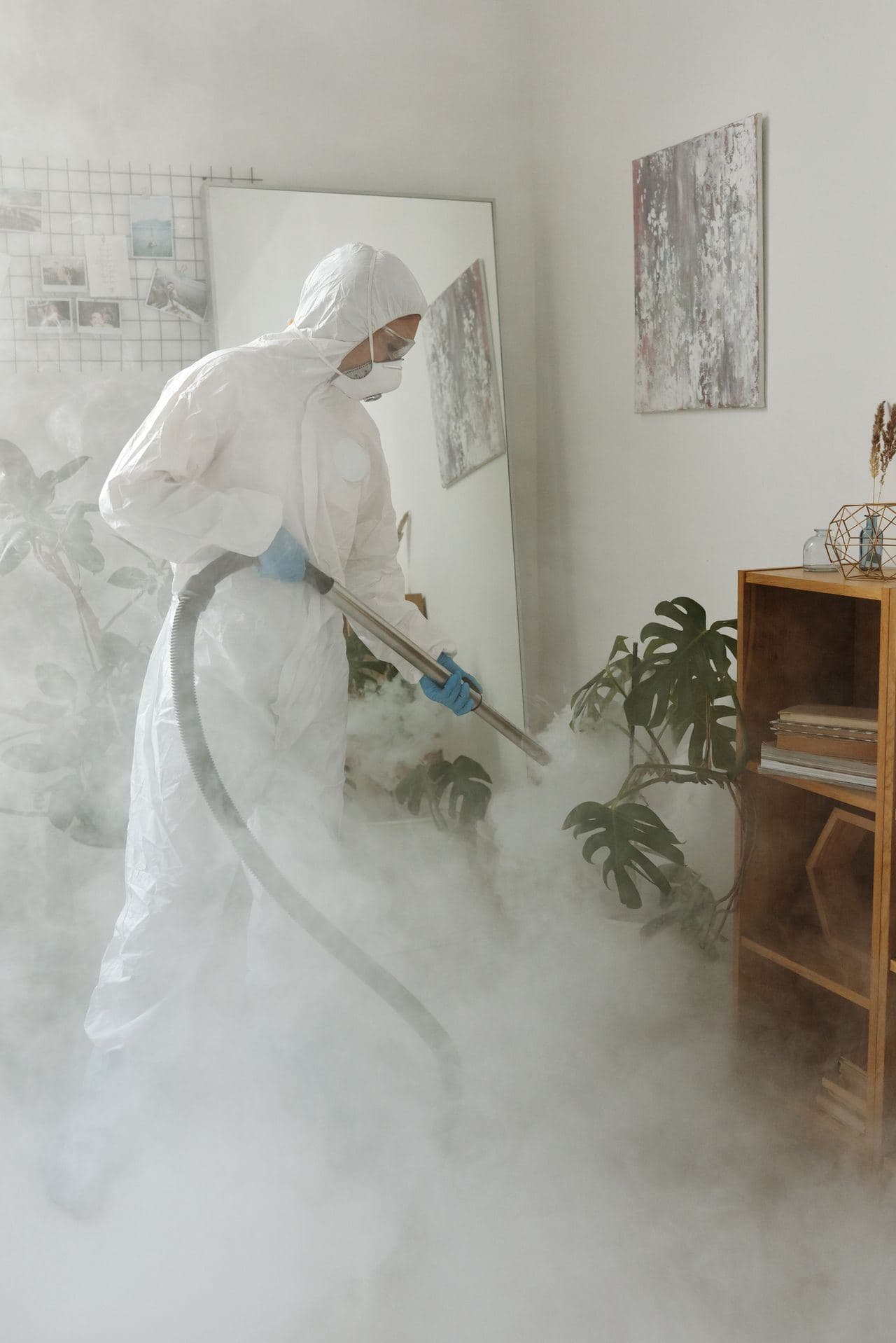 A technician in protective gear fogging a room to neutralize smoke odor at the source