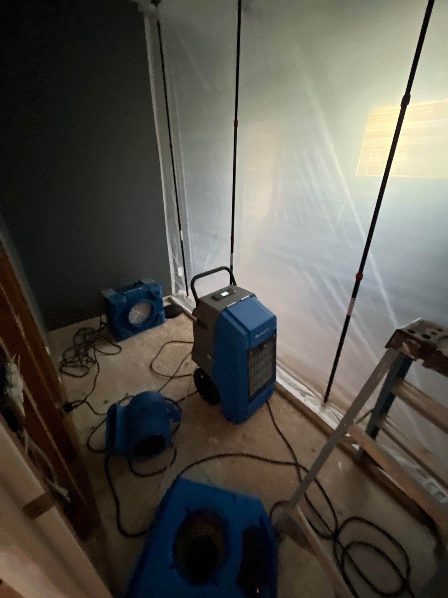 A HEPA air scrubber running behind containment sheeting on a Resolve Residential Restoration job