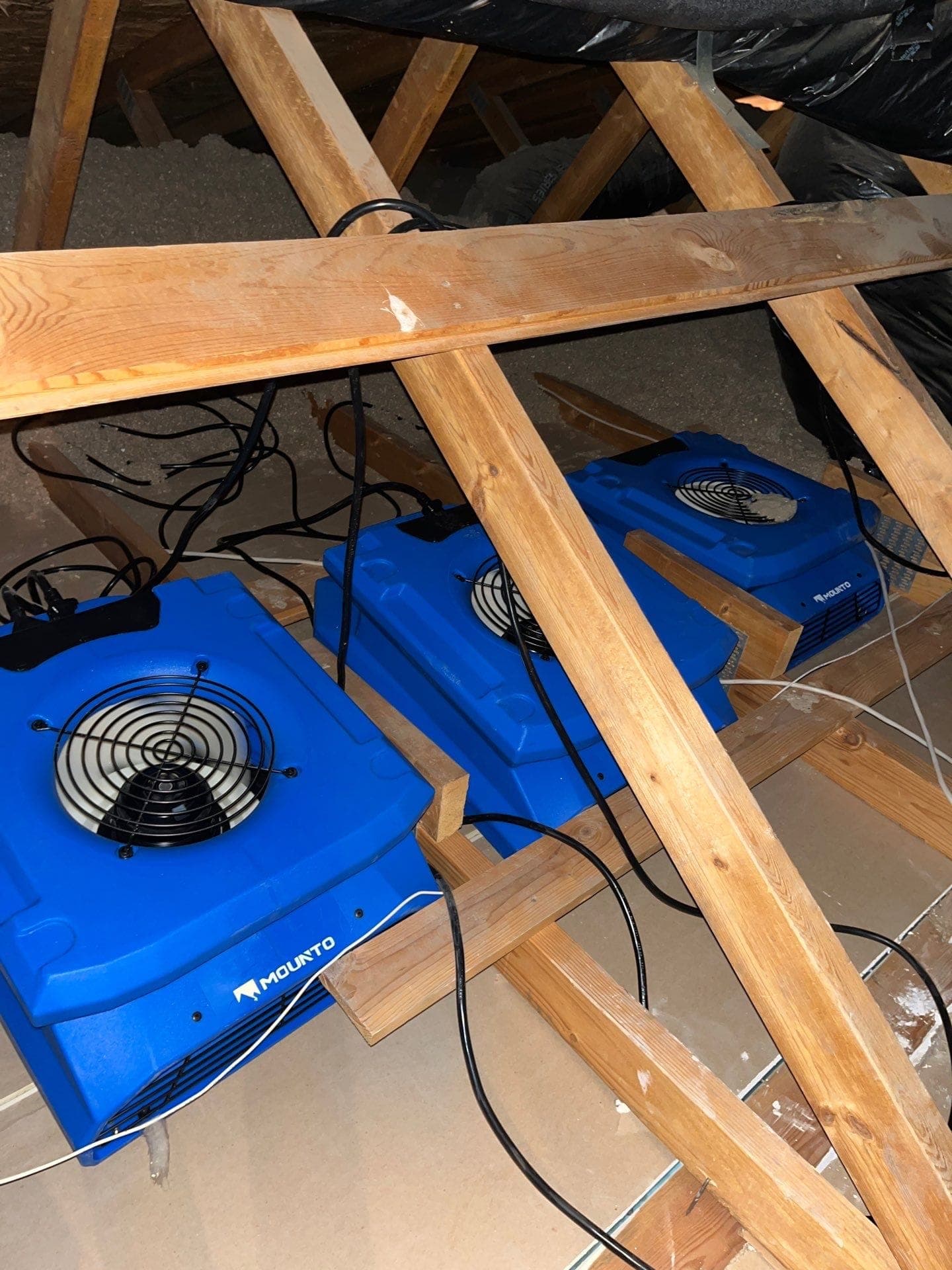 Air movers positioned among exposed attic rafters during a Resolve Residential Restoration structural dry-out