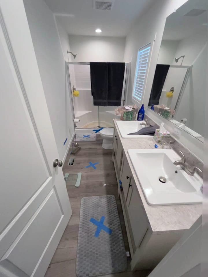 A bathroom floor being dried with marked moisture points on a Resolve Residential Restoration water-damage job