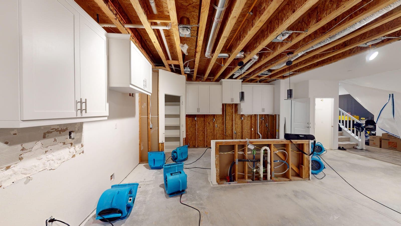 Air movers running in a kitchen opened to the joists during a Resolve Residential Restoration dry-out