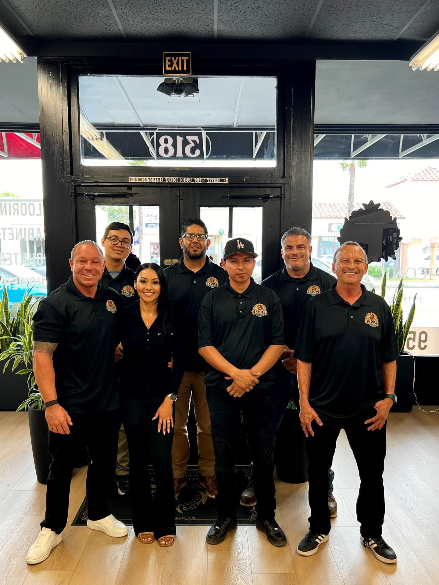 The Resolve team of seven standing together at the storefront entrance