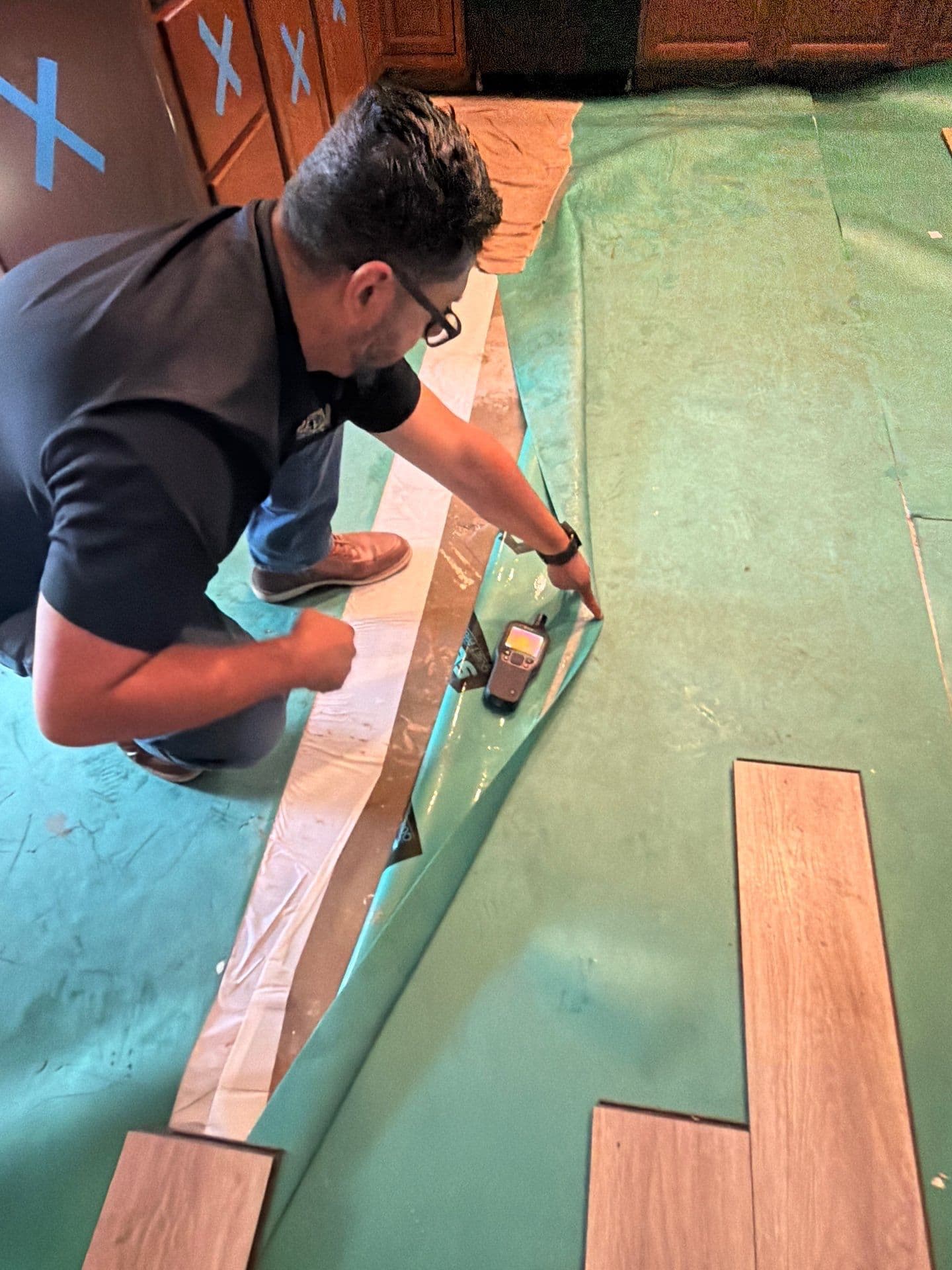 Resolve Residential Restoration technician lifting a moisture barrier to test a subfloor for trapped moisture