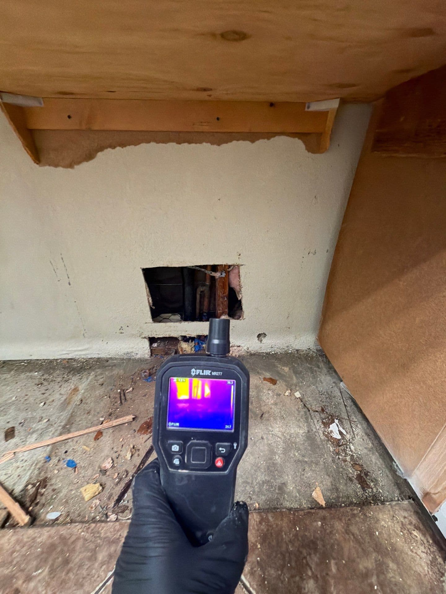 A Resolve Residential Restoration technician using thermal imaging at an opened wall to trace hidden moisture