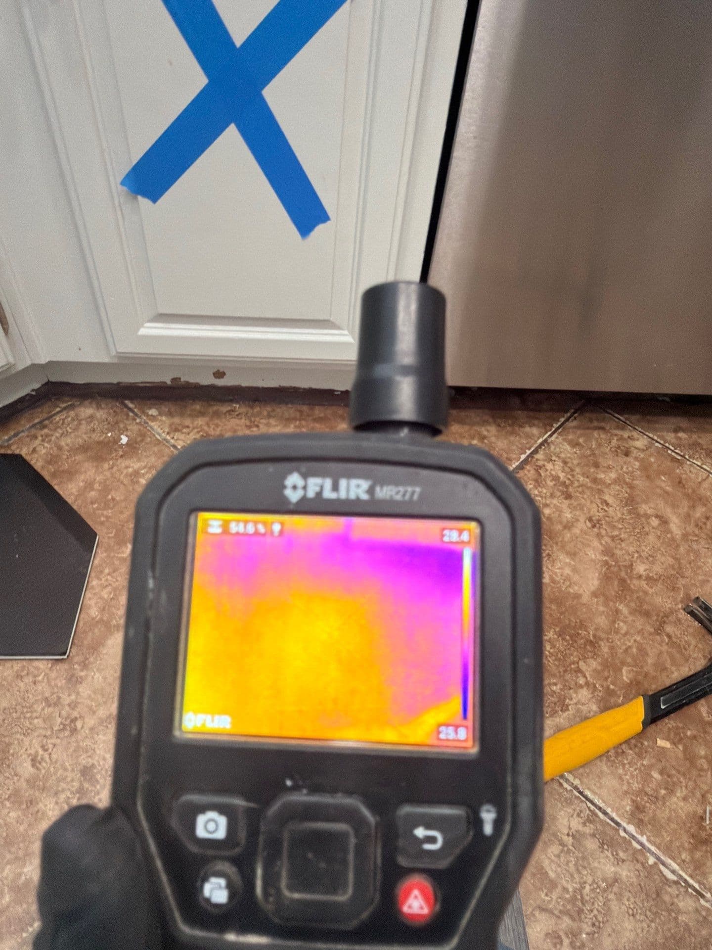 A thermal camera being used to trace moisture behind kitchen cabinets